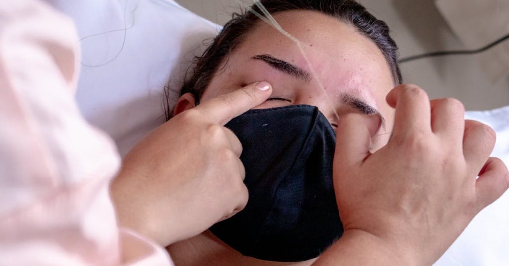 Close-up of a beauty treatment session with eyebrow threading on a relaxed woman wearing a mask.